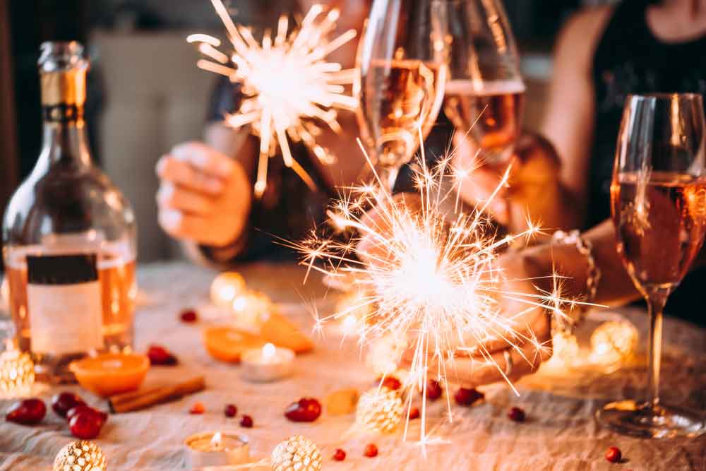 people celebrating new years eve with sparklers at dinner