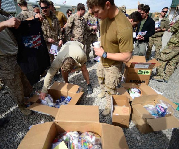 soldiers opening care packages outside on the concrete